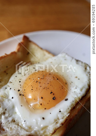 Buttered toast topped with soft-boiled fried egg 69194285