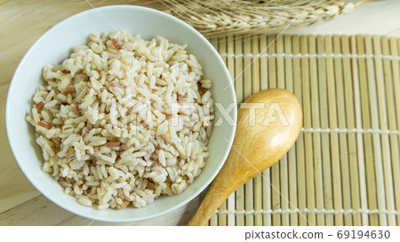 BROWN RICE in white bowl on wood table for health food content. BROWN RICE in white bowl on wood table for health food content. 69194630
