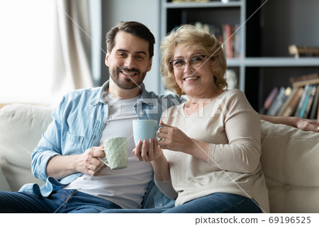 Head shot portrait smiling man with mature mother drinking tea 69196525