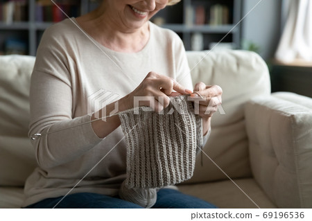 Close up smiling mature woman knitting at home Close up smiling mature woman knitting at home 69196536