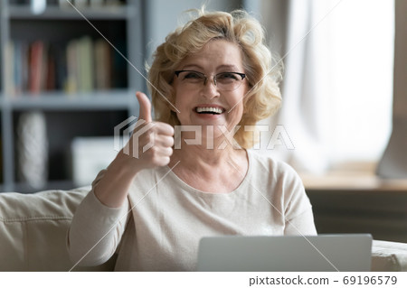 Head shot portrait smiling mature woman showing thumb up Head shot portrait smiling mature woman showing thumb up 69196579