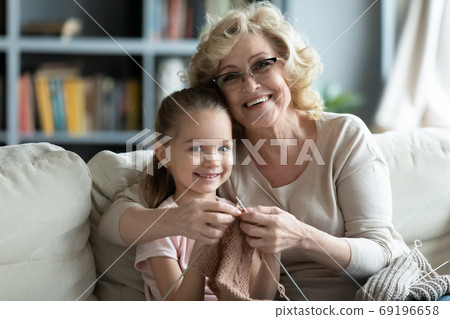 Head shot portrait smiling mature woman teaching little girl knitting Head shot portrait smiling mature woman teaching little girl knitting 69196658