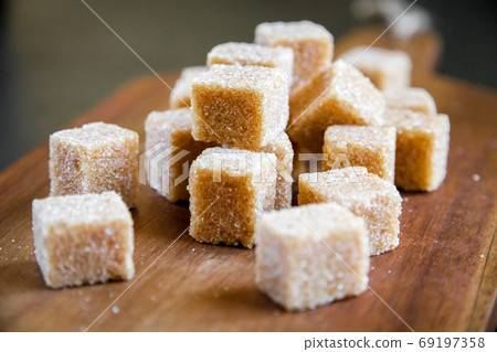 Brown cane sugar cubes on a cutting board Brown cane sugar cubes on a cutting board 69197358