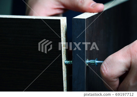 Assembling furniture at home. Hands whirl the fastener. Assembling furniture at home. Hands whirl the fastener. 69197712