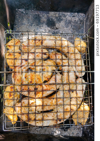 Top view of baked sausages and pieces of meat on a grill in the grill. Top view of baked sausages and pieces of meat on a grill in the grill. 69197713