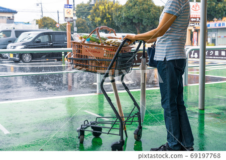 Shopping on a rainy day A woman with an ecological basket waiting for the rain to stop 69197768