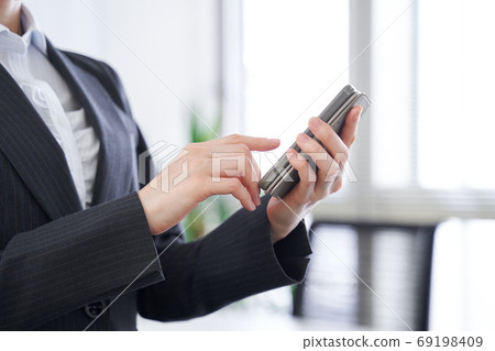 Japanese female business woman operating a smartphone in the office Japanese female business woman operating a smartphone in the office 69198409