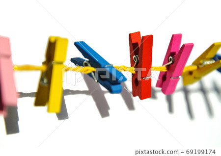 colored wooden clothespins on a yellow rope on a white background with shadow 69199174