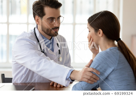 Close up caring doctor therapist touching frustrated patient shoulder Close up caring doctor therapist touching frustrated patient shoulder 69199324