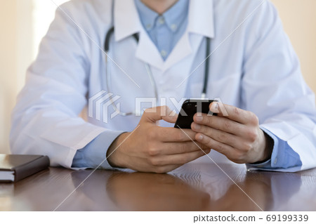 Close up doctor wearing uniform holding phone, using medical apps 69199339