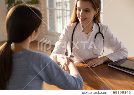 Smiling female doctor therapist shaking patient hand at meeting 69199346