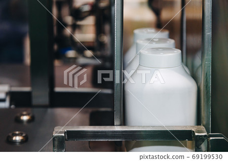 white plastic bottle of baby powder products in conveyor belt moving to packing machine in the cosmetic factory. white plastic bottle of baby powder products in conveyor belt moving to packing machine in the cosmetic factory. 69199530
