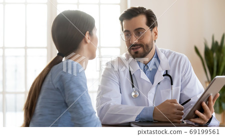 Doctor therapist consulting patient at meeting, using computer tablet 69199561