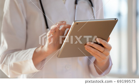 Close up young woman doctor holding computer tablet, using apps Close up young woman doctor holding computer tablet, using apps 69199575