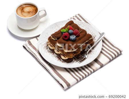 portion of Classic tiramisu dessert with raspberries, blueberries and cup of fresh hot espresso isolated on white background - clipping path 69200042