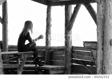 A girl sits in a wooden arbor on a foggy day and A girl sits in a wooden arbor on a foggy day and 69202352