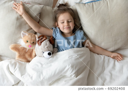 Little girl sleeping in bed with fluffy animal toys Little girl sleeping in bed with fluffy animal toys 69202408