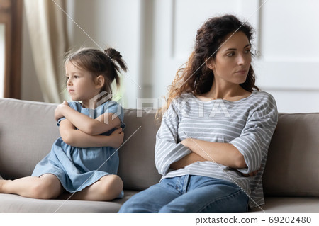 Mother disobedient daughter sit apart on sofa feeling discontent 69202480