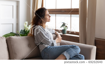 Beautiful pensive woman looking out window while resting on couch 69202640