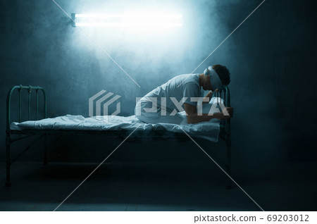 Blindfolded psycho man sitting in bed, hospital 69203012
