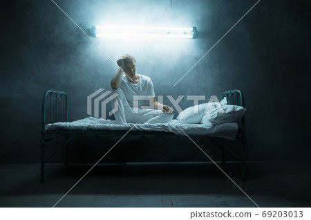 Psycho man sitting in bed, dark room on background Psycho man sitting in bed, dark room on background 69203013