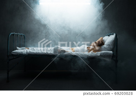 Psycho woman lying in bed, dark room on background Psycho woman lying in bed, dark room on background 69203028