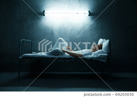 Psycho man lying in bed, dark room on background 69203030