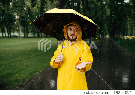 Man with umbrella walking in park in rainy day Man with umbrella walking in park in rainy day 69203094