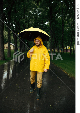Man with umbrella walking in park in rainy day Man with umbrella walking in park in rainy day 69203100