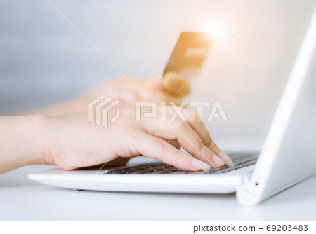 Hands holding credit card on the keyboard online shopping on lap Hands holding credit card on the keyboard online shopping on lap 69203483