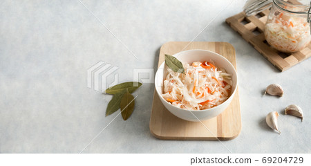 White ceramic bowl with homemade appetizer sauerkraut on a light, concrete background. Glass jar and spices garlic and bay leaf. Close up with copy space White ceramic bowl with homemade appetizer sauerkraut on a light, concrete background. Glass jar and spices garlic and bay leaf. Close up with copy space 69204729