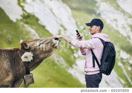 Happy traveler with cow in mountain 69205809