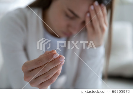 Frustrated young girl holding engagement diamond ring, divorce concept. Frustrated young girl holding engagement diamond ring, divorce concept. 69205973