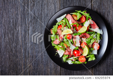 Sliced beef tagliata salad on a plate, free space 69205974