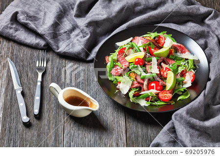 Tagliata sirloin steak salad on a black plate Tagliata sirloin steak salad on a black plate 69205976