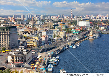 The landscape of summer Kyiv with a view of the Dnipro embankment in the old Podol district, piers and pleasure boats. The landscape of summer Kyiv with a view of the Dnipro embankment in the old Podol district, piers and pleasure boats. 69207958