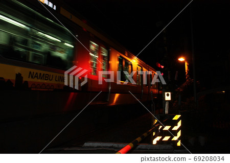 Train reflected in a red warning light in the darkness of night 69208034