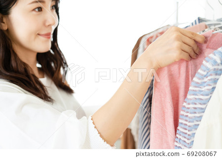 A smiling young woman choosing clothes is in focus 69208067