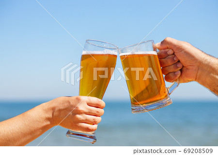 closeup hands holding glasses of beer closeup hands holding glasses of beer 69208509