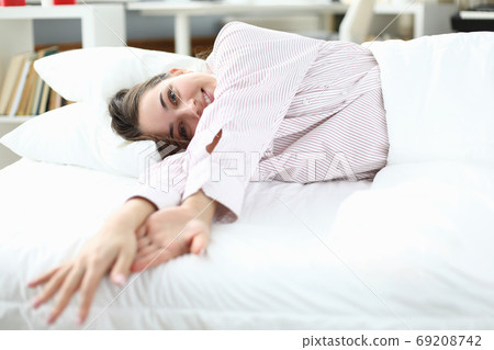 Woman lies in bed in shirt and smiles. closeup Woman lies in bed in shirt and smiles. closeup 69208742