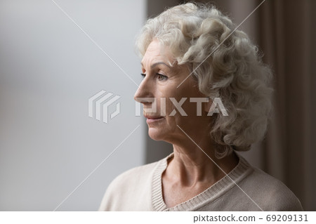 Close up upset thoughtful mature senior woman looking out window Close up upset thoughtful mature senior woman looking out window 69209131