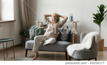 Peaceful satisfied mature woman relaxing on comfortable sofa at home Peaceful satisfied mature woman relaxing on comfortable sofa at home 69209177