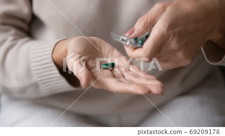 Close up mature woman taking pill out of packaging Close up mature woman taking pill out of packaging 69209178
