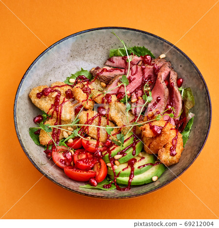fresh summer salad with of fried beef and avocado, with shrimp and banana breadcrumbs over orange background. fresh summer salad with of fried beef and avocado, with shrimp and banana breadcrumbs over orange background. 69212004