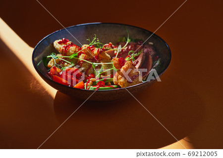 fresh summer salad with grilled beef and avocado, shrimps and banana breadcrumbs on an orange background. fresh summer salad with grilled beef and avocado, shrimps and banana breadcrumbs on an orange background. 69212005