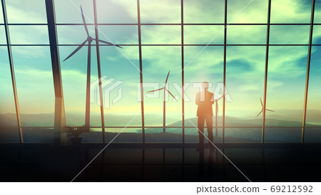 In a spacious office against the window, a man looks at wind farms. 69212592
