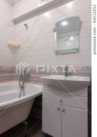 A fragment of the interior of a conventional bathroom with a washbasin and an acrylic bathtub 69212652