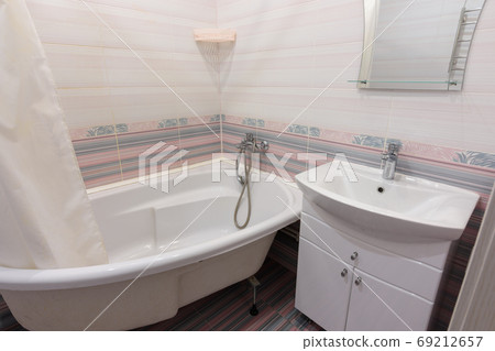 Interior of a cozy ordinary bathroom with a washbasin, a bathtub and a mirror 69212657