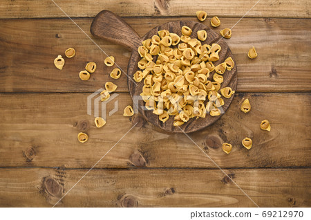Tortellini mignon on a wooden board l and parmesan. Specialties of the cuisine from Bologna and 69212970
