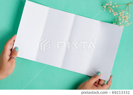 White mockup paper brochure in a woman's hand. White mockup paper brochure in a woman's hand. 69213332